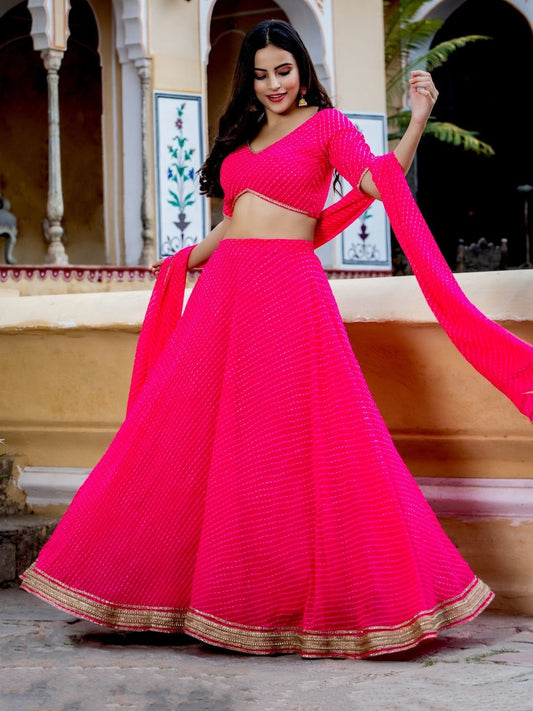 Woman twirling in a bright hot pink lehenga choli with golden border – ideal for weddings, sangeet, and festive occasions.


