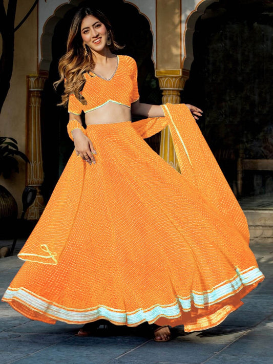 Woman twirling in a vibrant orange lehenga choli with light blue border – perfect for haldi or festive daywear